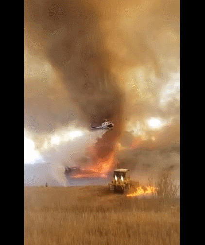 将地面的火苗和浓烟卷起数十米高,而空中有消防局的灭火直升飞机,地面