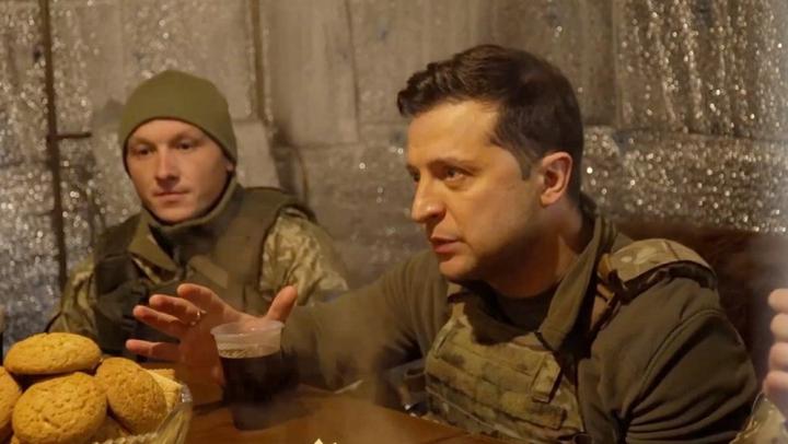 Volodymyr Zelensky 坐在避难所的一张桌子旁，与军方交谈。