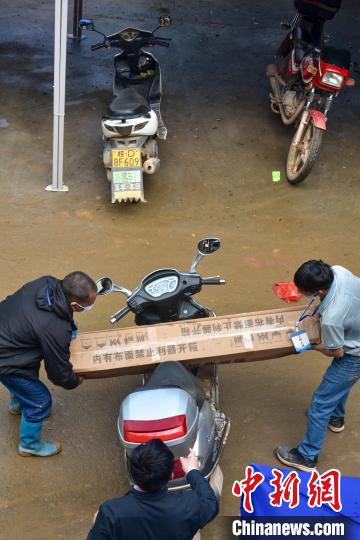 兩名村民將救援物資抬上一輛踏板摩托車。 王以照攝