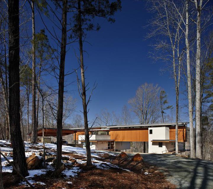 A house is pictured over looking a hill with snow on the ground. 