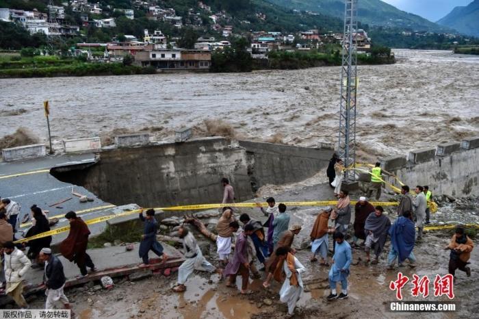 据巴基斯坦《黎明报》26日报道，巴基斯坦最近一段时间以来，强降雨引发洪水等灾害已致937人死亡、3000万人无家可归。巴政府官员称进入“国家紧急状态”。图为巴基斯坦斯瓦特河谷，人们聚集在被强降雨毁坏的道路旁。