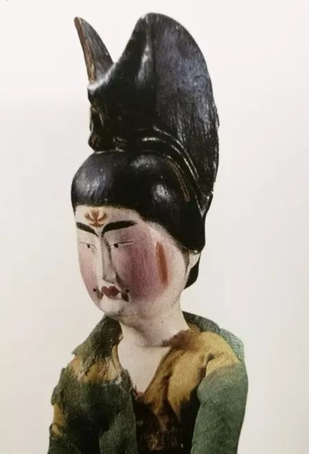 新疆吐鲁番市阿斯塔那206号墓出土,头梳高髻,饰花钿,斜红和面靥并点唇