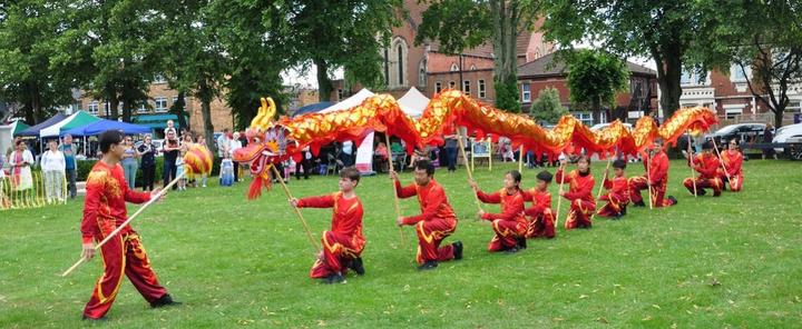 A group of people performing a dragon dance

Description automatically generated