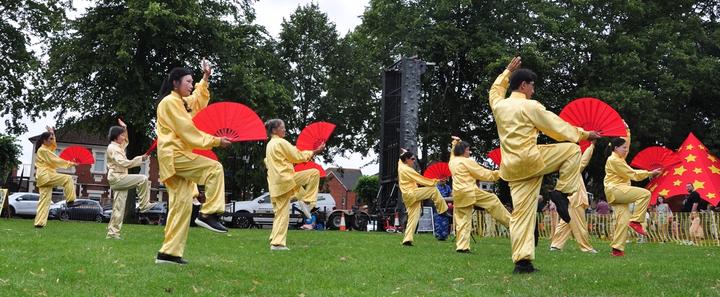 A group of people in yellow uniforms holding red fans

Description automatically generated