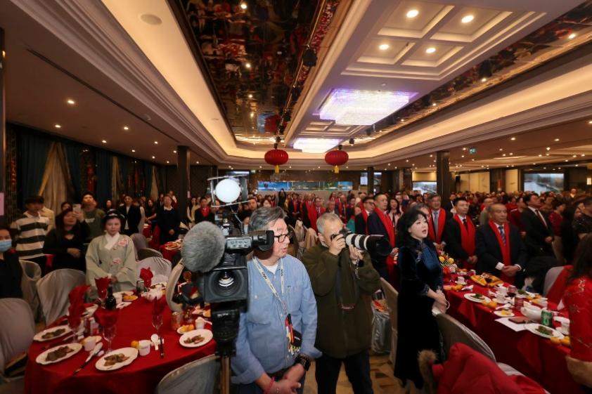 A group of people in a room with red tablecloths

Description automatically generated