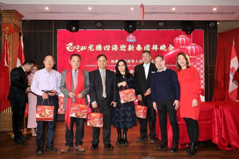 A group of people standing in front of a red backdrop

Description automatically generated