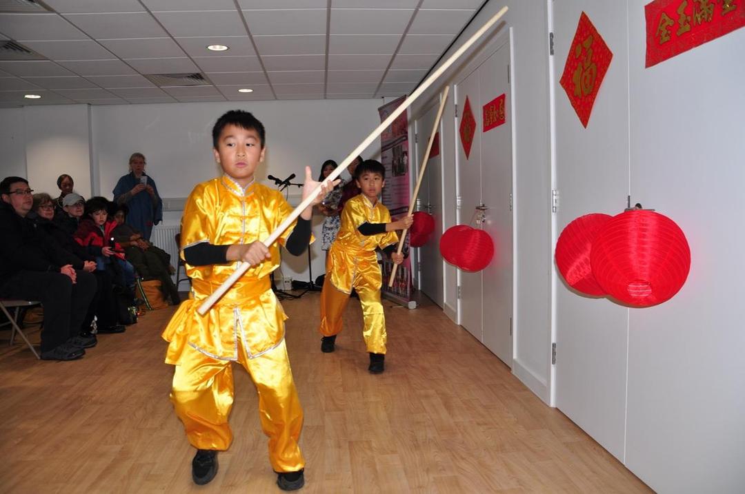 A group of young boys in yellow robes holding a stick

Description automatically generated