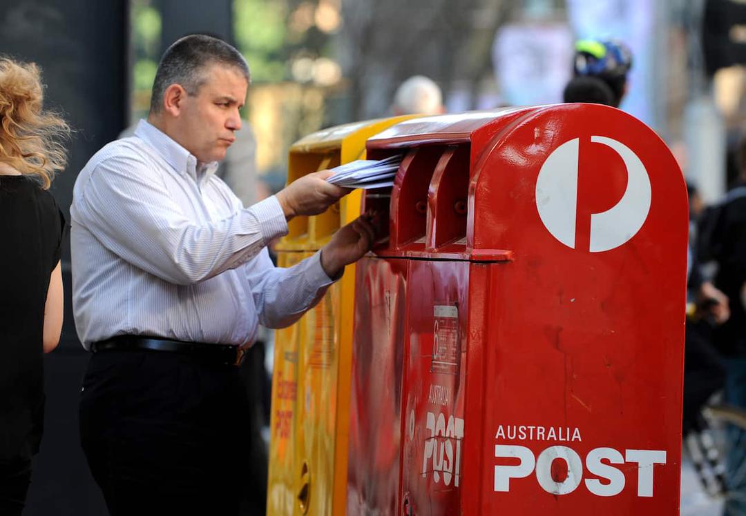 A man inserts letters into an Australia Post post box in Syndey's CBD.