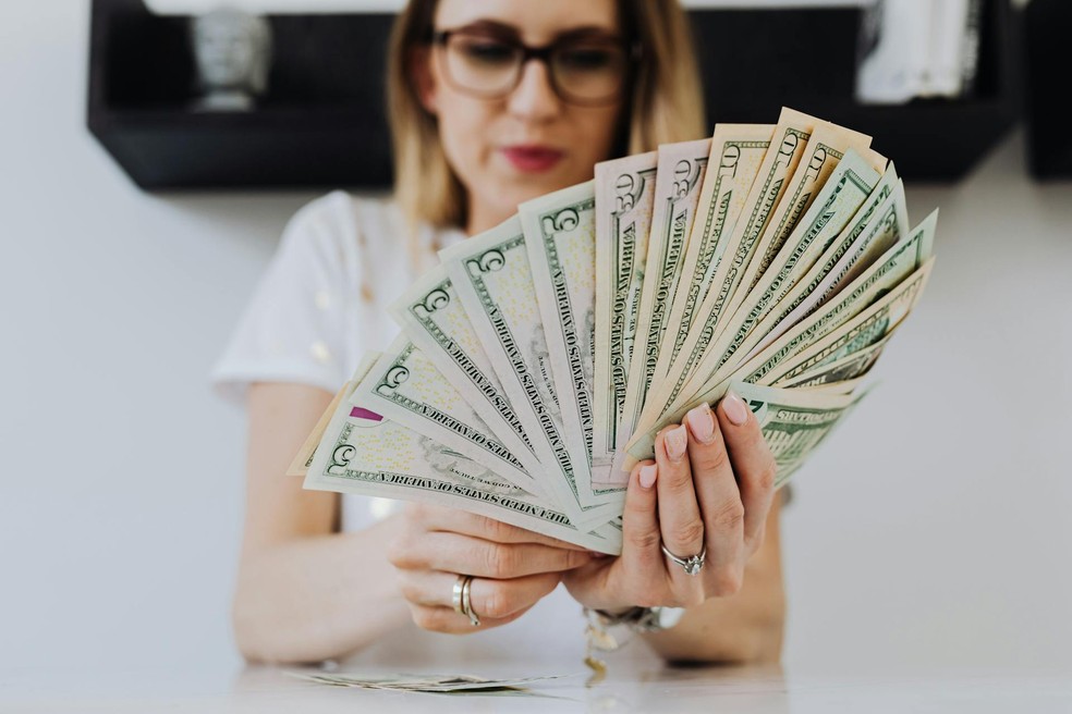 Mulher segura notas de dólar, dinheiro — Foto: Karolina Grabowska/Pexels