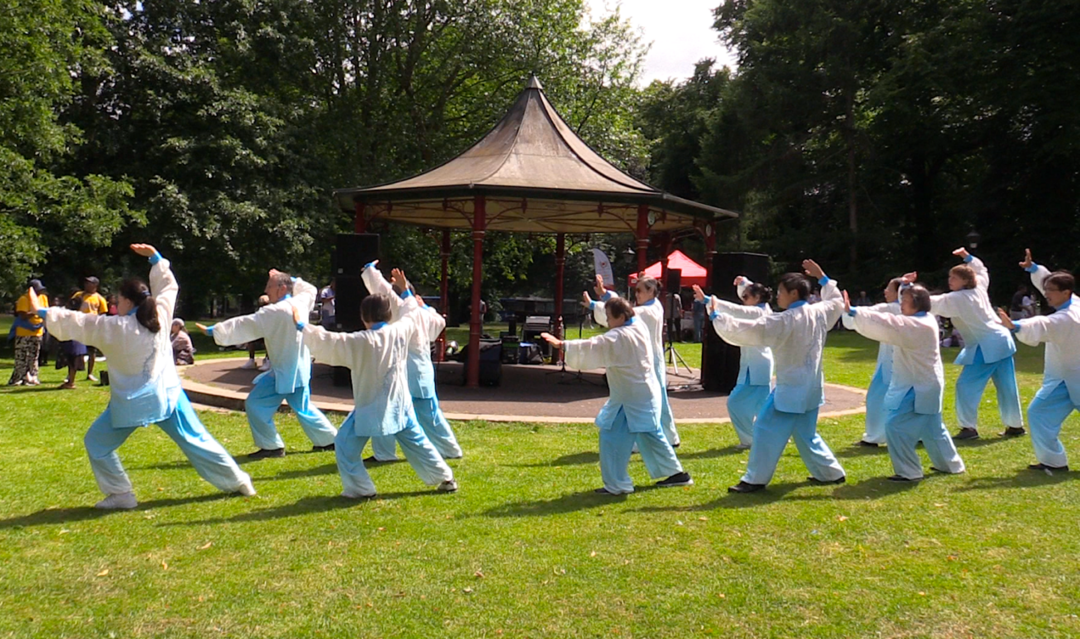 A group of people in white shirts and blue pants doing tai chi

Description automatically generated