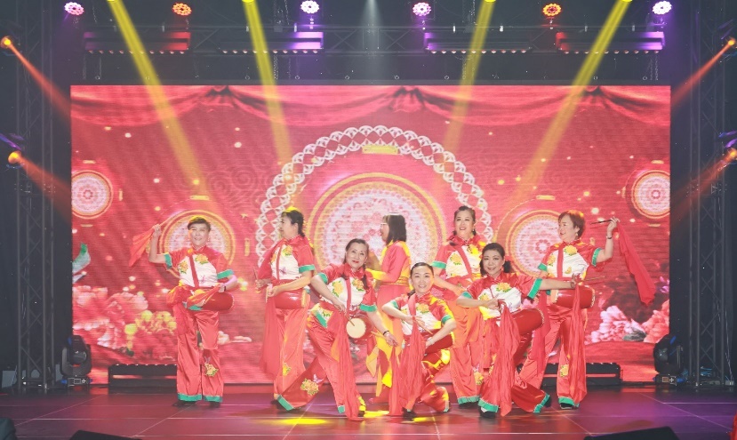 A group of people in red dresses on a stage Description automatically generated