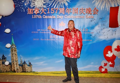 A person in a red shirt pointing at a large banner Description automatically generated