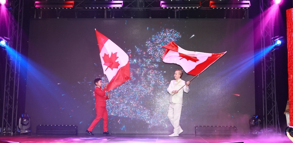 Two people holding flags on a stage Description automatically generated