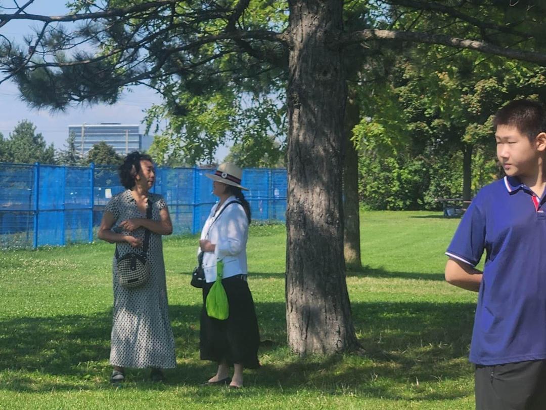 A group of people standing under a treeDescription automatically generated