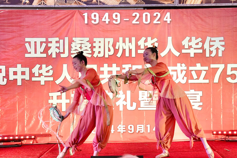 Two women in pink outfits dancing on a stage

Description automatically generated