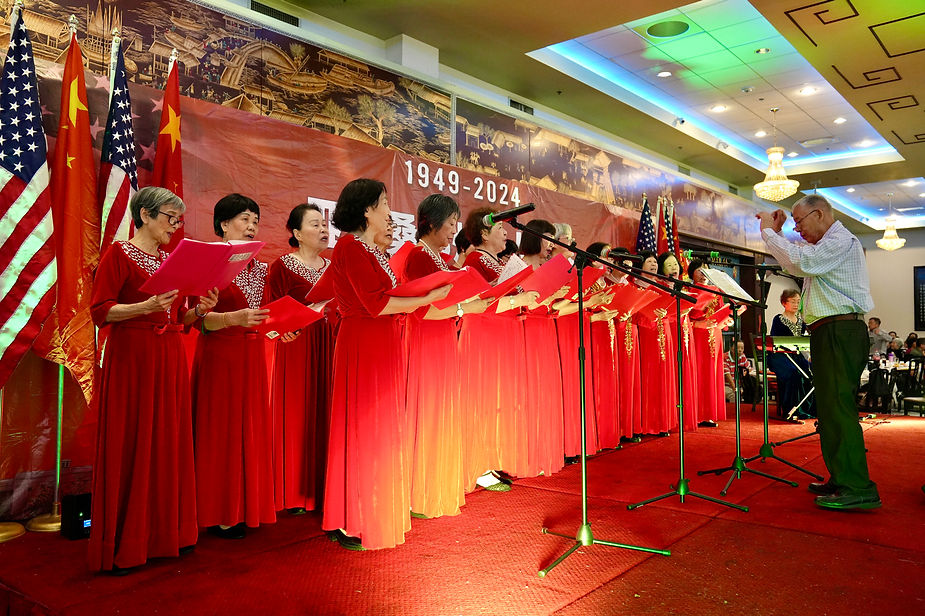 A group of women singing in red dresses

Description automatically generated