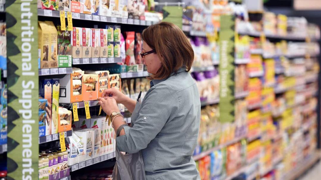 A lady stacking shelves at a asupermarket.