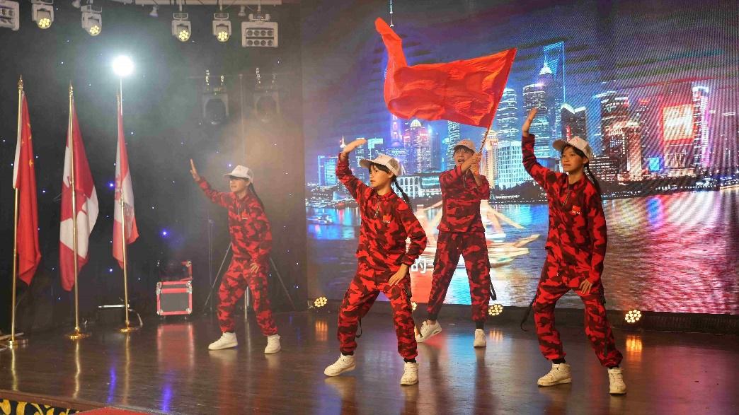 A group of people in red and black outfits on a stageDescription automatically generated