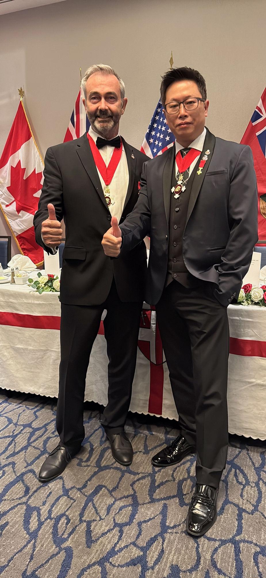 Two men in suits giving thumbs up

Description automatically generated