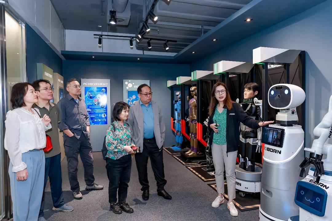 A group of people standing in a room with machines

Description automatically generated