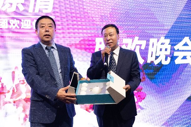 Two men in suits holding a microphone and a box with eggs

Description automatically generated