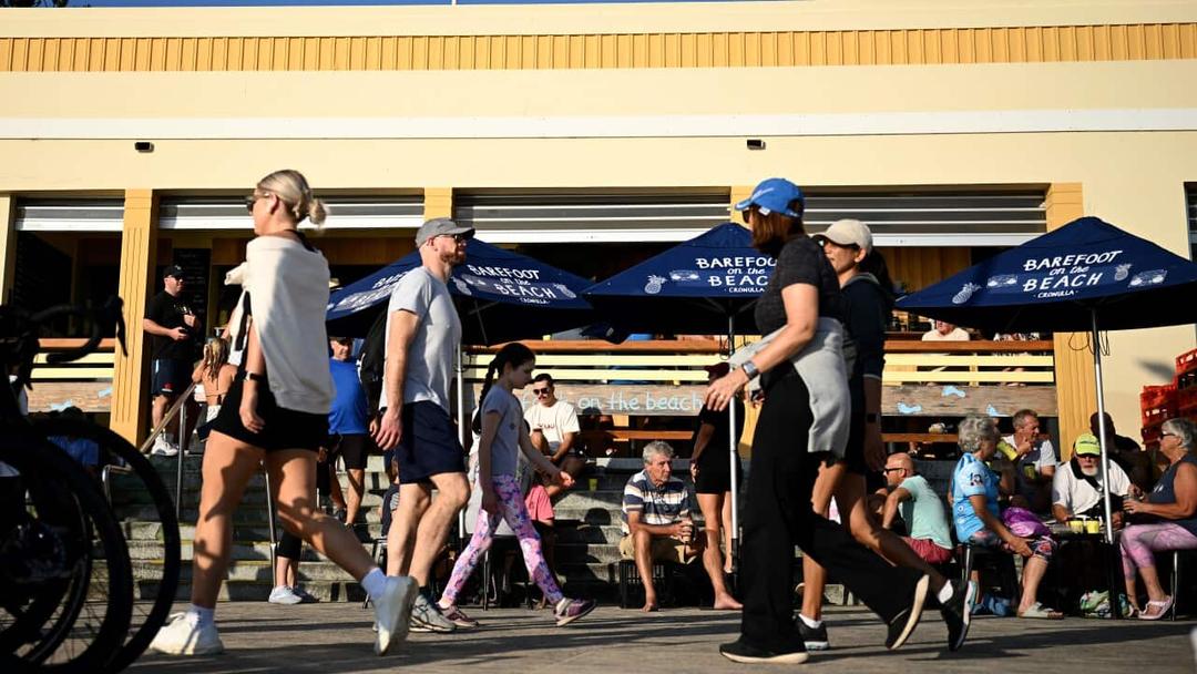 People walking past a cafe on the foreshore. 