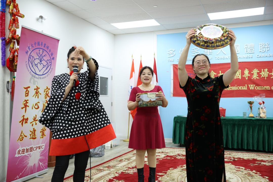 A group of women holding a plate and a microphoneDescription automatically generated