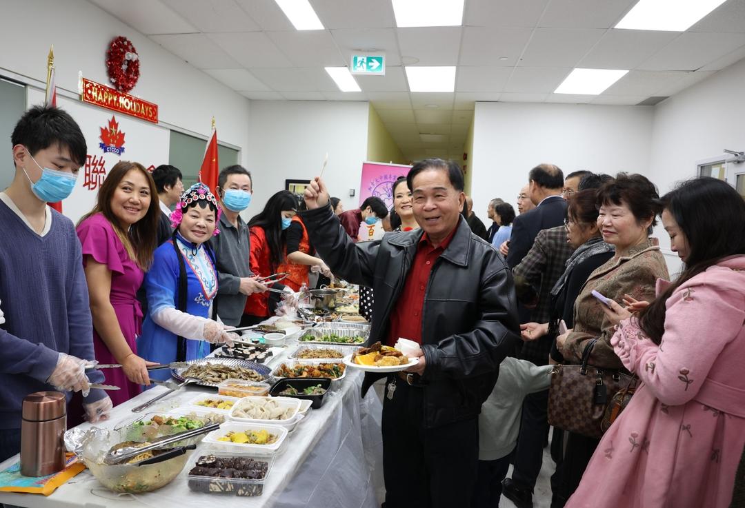 A group of people standing around a table full of foodDescription automatically generated