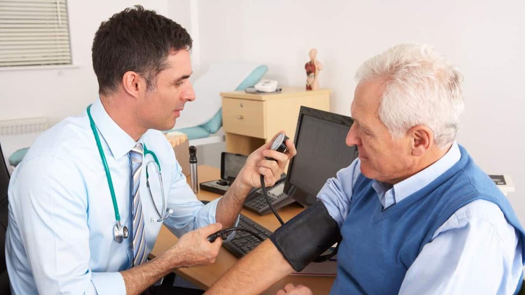 A male doctor taking senior man's blood pressure