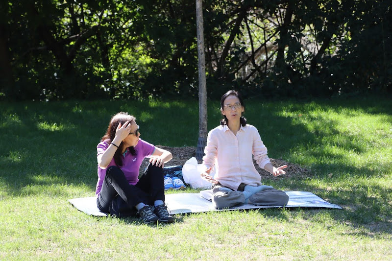 A group of people sitting on a mat in the grassAI-generated content may be incorrect.