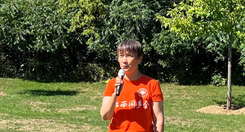 A person in an orange shirt holding a microphoneAI-generated content may be incorrect.