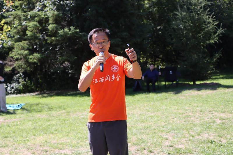 A person in an orange shirt holding two microphonesAI-generated content may be incorrect.