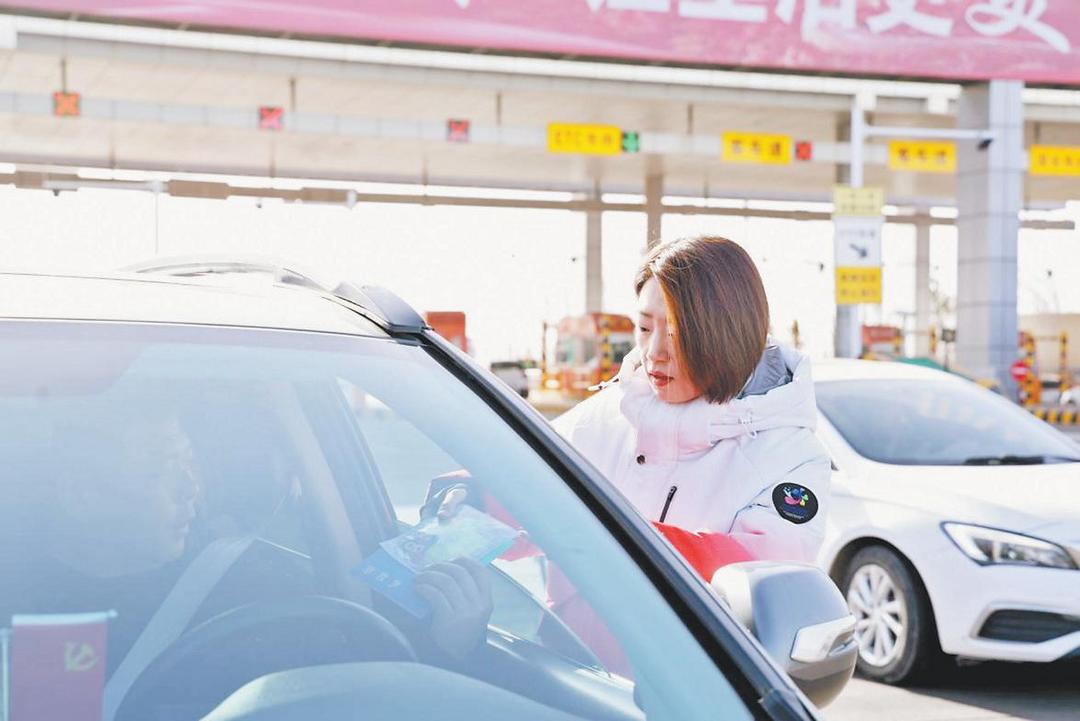 志愿者为司乘人员发放志愿服务手册。