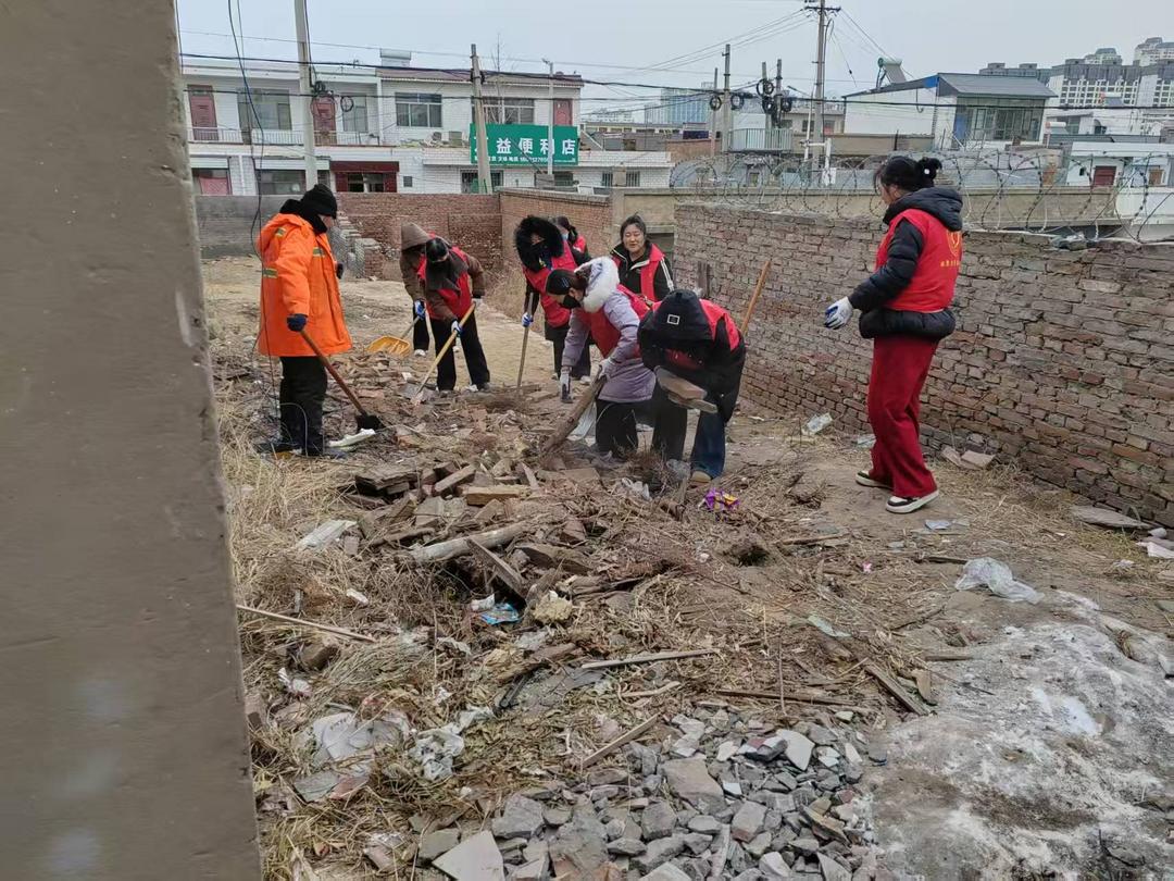 工作人员手持铁锹、扫帚等工具，对堆积的砖块、碎石、枯枝杂草、生活垃圾等进行全面清理