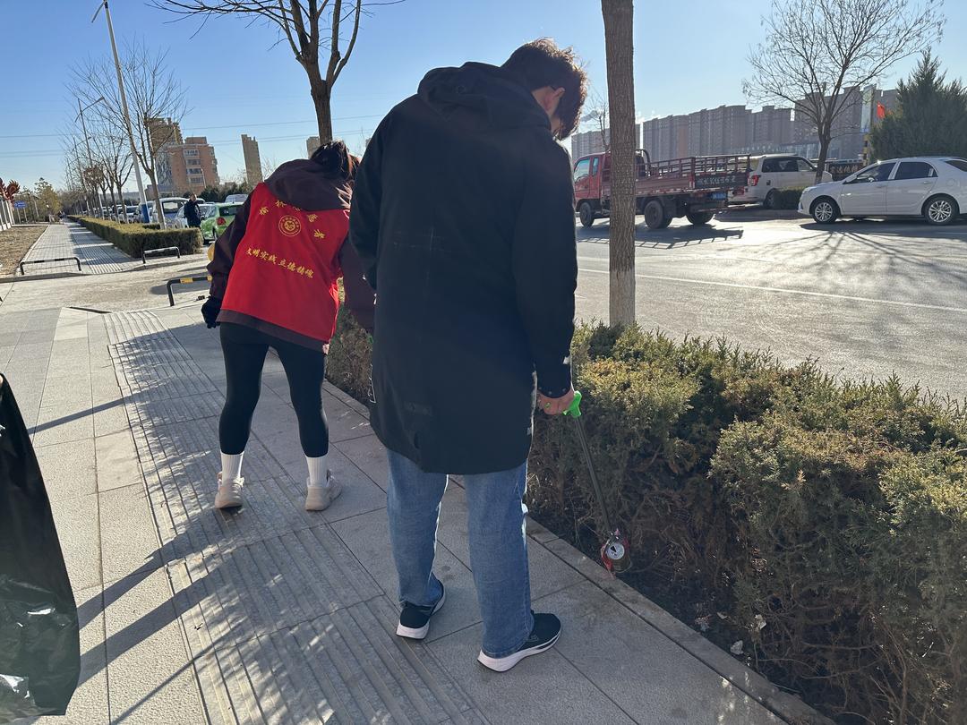 社区工作人员及志愿者清理辖区周边绿化带、空闲地垃圾废物