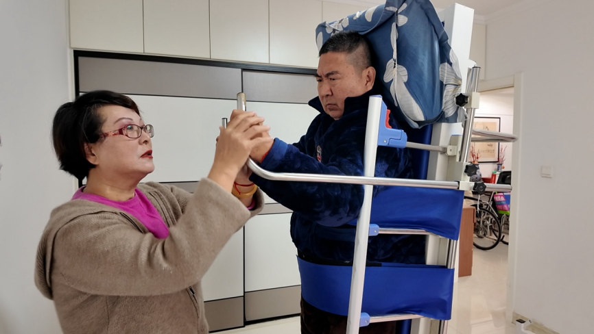 这是山东省滨州市滨城区的一对夫妻，丈夫因病瘫痪，需要坚持康复治疗。滨州市在职工长护险待遇中，增加了辅具租赁项目，这个康复床租用每月仅需100多元，不仅减轻了病患家庭经济压力，还免去了奔波去医院做康复的麻烦，在家里就能进行康复