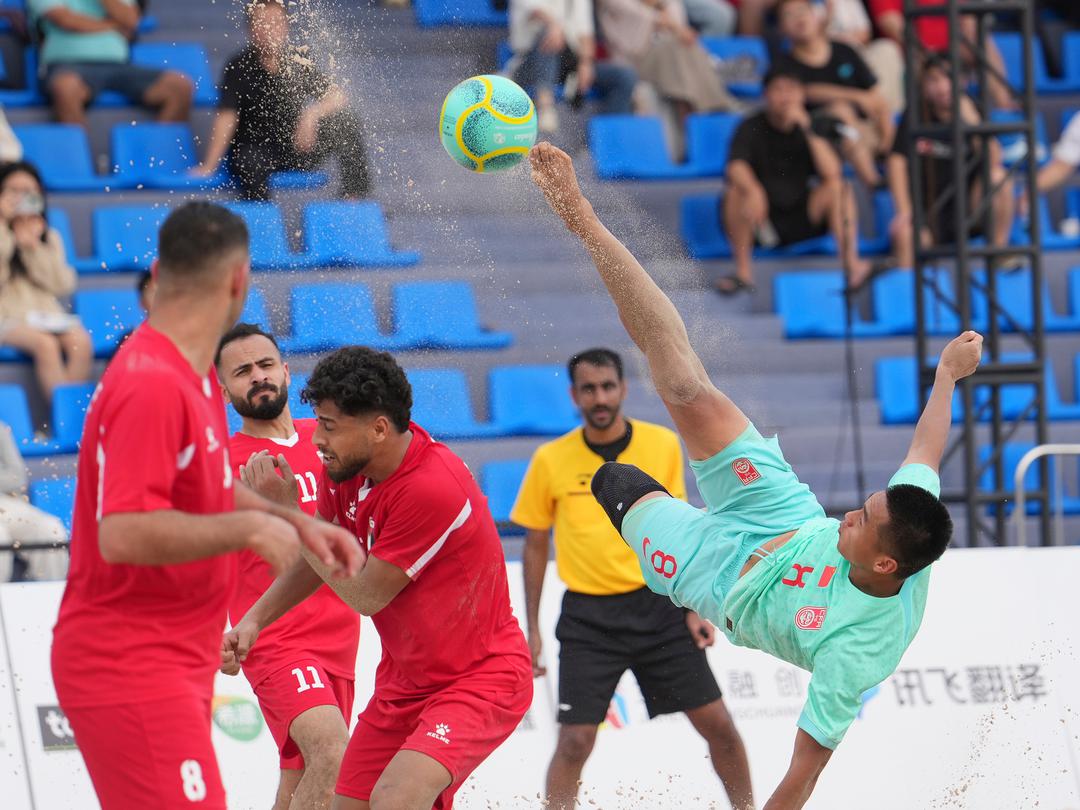4月25日，在海南三亚举行的第六届亚洲沙滩运动会沙滩足球男子小组赛中，中国队3比4不敌巴勒斯坦队。中国队球员刘浩然（右）在比赛中倒钩射门。（来源：第六届亚洲沙滩运动会组委会）